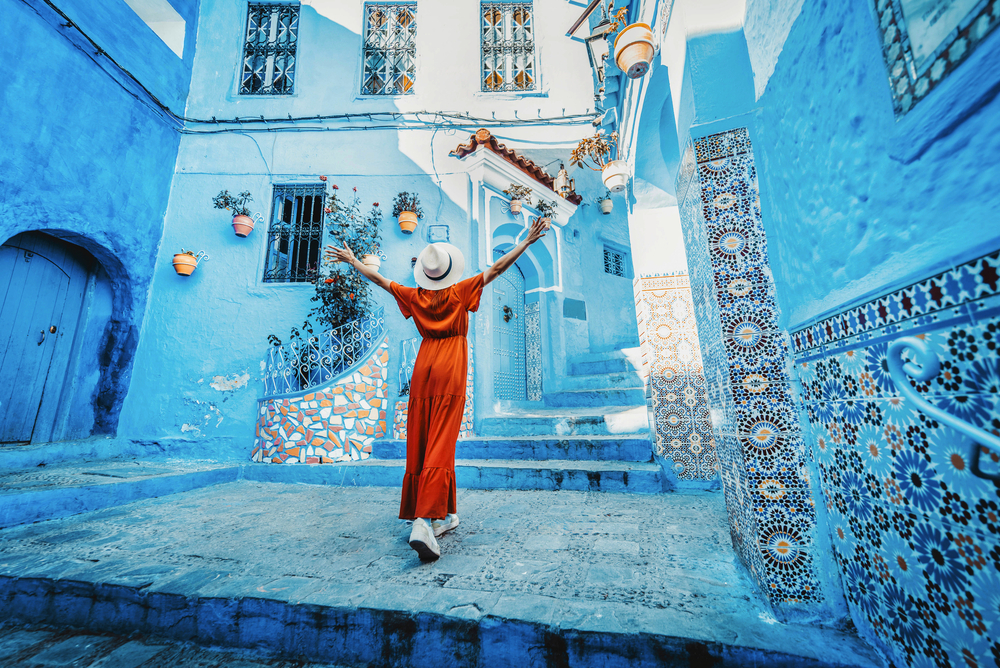 Frau mit rotem Kleid besucht die blaue Stadt Chefchaouen in Marokko