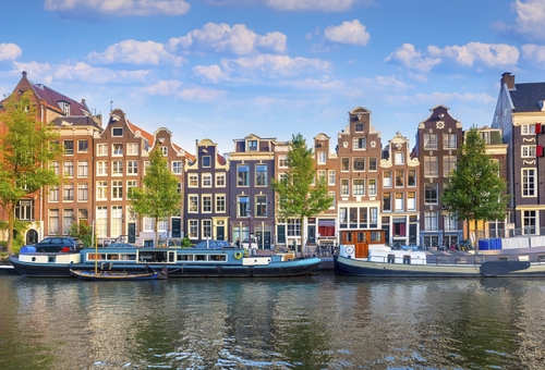 Amsterdam. Panoramablick auf das historische Stadtzentrum von Amsterdam. Traditionelle Häuser und Brücken von Amsterdam. Ein früher, ruhiger Morgen und die ruhige Reflexion der Häuser im Wasser. Europa